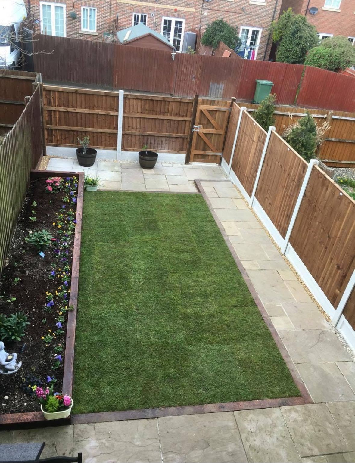 Garden transformation with patio slabs, artificial grass, and flower beds